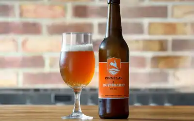 Copo de cerveja Amber Ale de cor âmbar profunda com espuma bege